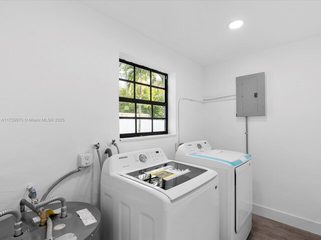 washroom with washing machine and clothes dryer, electric panel, and dark wood-type flooring