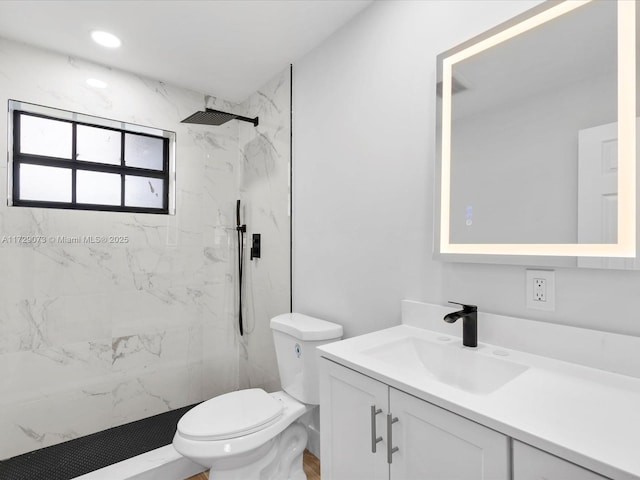 bathroom featuring tiled shower, toilet, and vanity