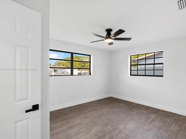 spare room with a healthy amount of sunlight, ceiling fan, and dark hardwood / wood-style flooring