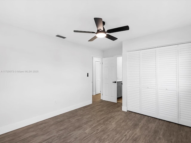 unfurnished bedroom with ceiling fan, a closet, and dark hardwood / wood-style flooring