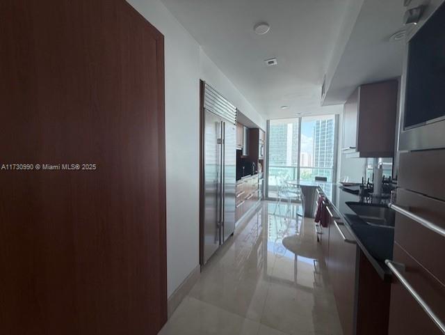 1331 Brickell Bay Dr Unit 1602, Miami, FL 33131 - kitchen with floor to ceiling windows, stainless steel built in fridge, light tile patterned floors, dark countertops, and modern cabinets