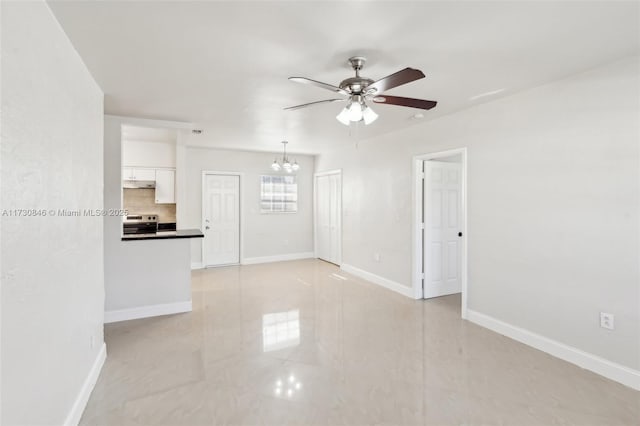 unfurnished living room featuring ceiling fan with notable chandelier