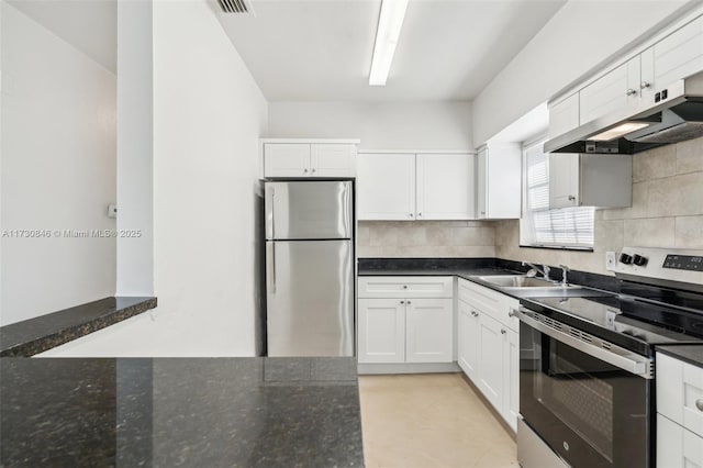 kitchen featuring appliances with stainless steel finishes, white cabinetry, sink, backsplash, and dark stone counters