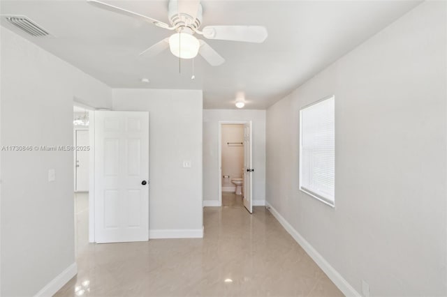 unfurnished bedroom with ceiling fan, multiple windows, and connected bathroom