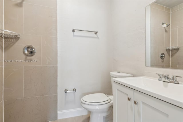 bathroom with tiled shower, toilet, and vanity