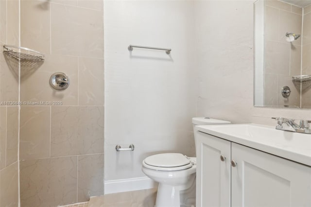 bathroom featuring toilet, vanity, and a tile shower