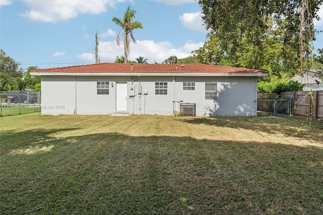 back of property with central air condition unit and a lawn