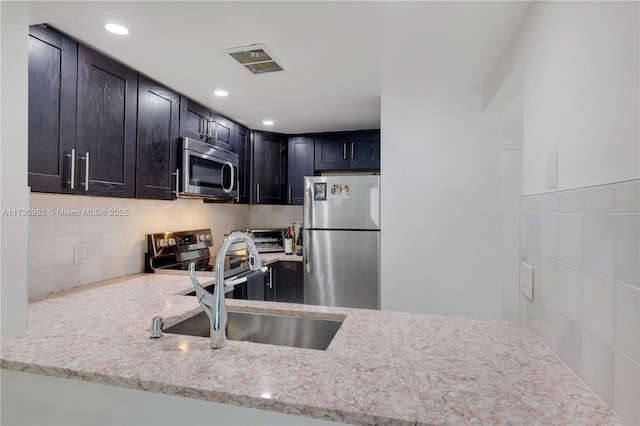 kitchen featuring light stone countertops, stainless steel appliances, and sink