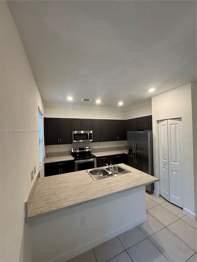 kitchen with sink, stainless steel appliances, kitchen peninsula, and light tile patterned flooring