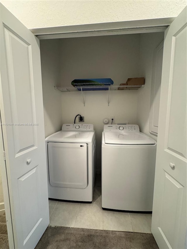 laundry area with washer and clothes dryer and light tile patterned floors