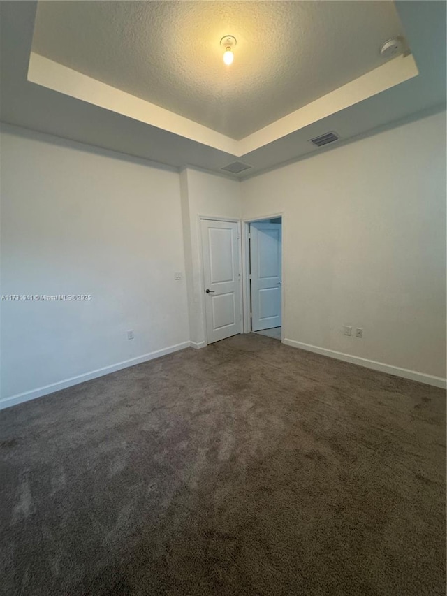 carpeted empty room with a tray ceiling and a textured ceiling