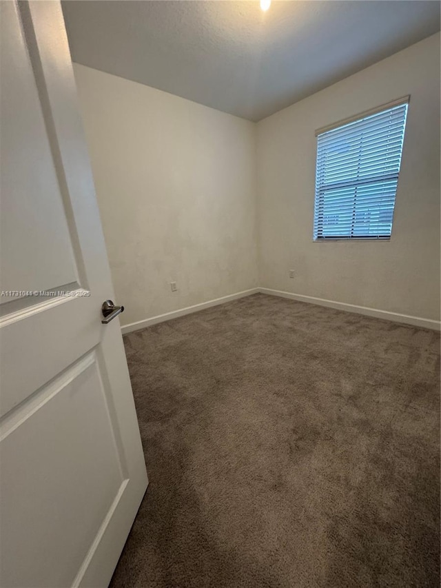 spare room featuring dark carpet