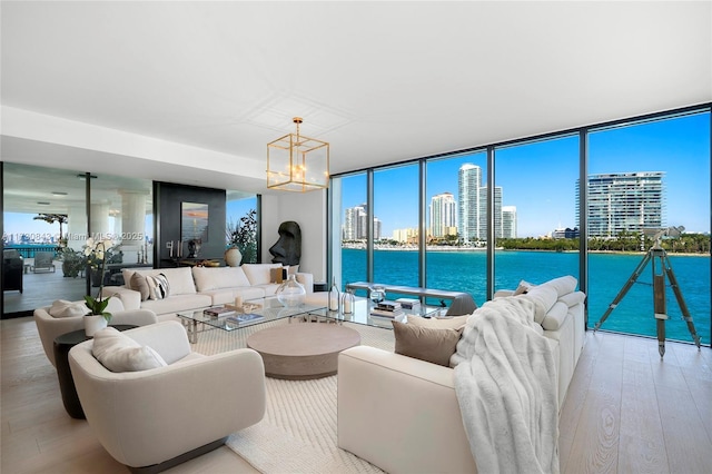 living room with a wealth of natural light, light hardwood / wood-style flooring, a chandelier, and a water view