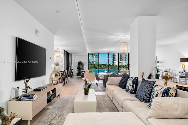 living room with expansive windows, a notable chandelier, and light wood-type flooring