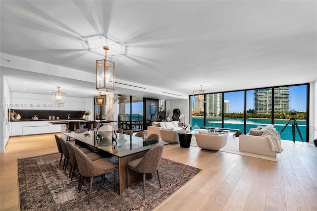 dining room featuring a water view, an inviting chandelier, and light hardwood / wood-style flooring