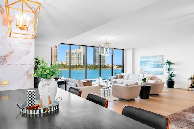 living room featuring an inviting chandelier, hardwood / wood-style flooring, a wall of windows, and a water view