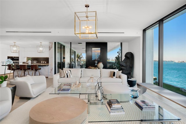 living room featuring floor to ceiling windows, a chandelier, and a water view