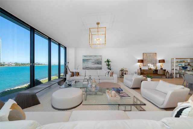 living room featuring a notable chandelier, floor to ceiling windows, a healthy amount of sunlight, and a water view