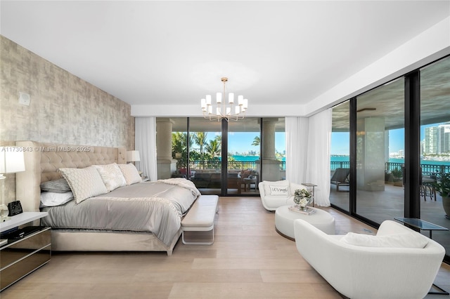 bedroom with an inviting chandelier, access to outside, light hardwood / wood-style floors, and a wall of windows