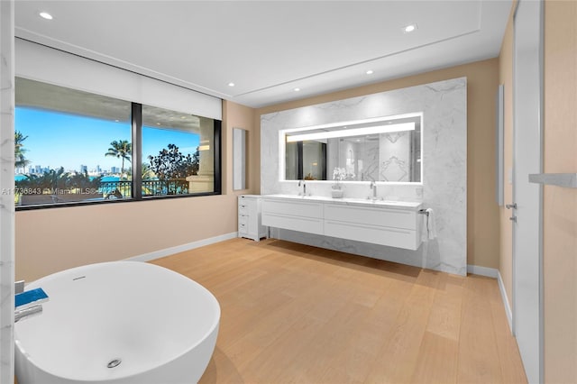 bathroom featuring vanity, hardwood / wood-style floors, and a bath