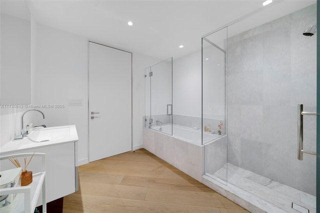 bathroom with vanity, hardwood / wood-style floors, and plus walk in shower