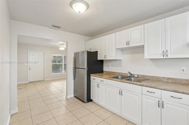 kitchen featuring sink, white cabinetry, stainless steel fridge, and light tile patterned flooring