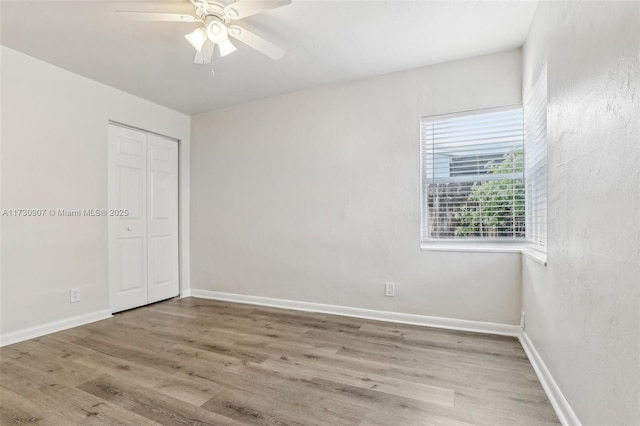 unfurnished bedroom featuring ceiling fan, hardwood / wood-style flooring, and a closet