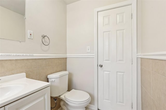 bathroom featuring vanity, toilet, and tile walls