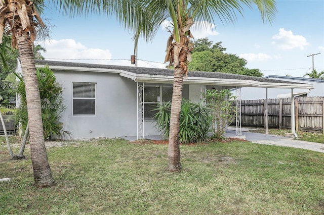 back of property featuring a lawn and a carport