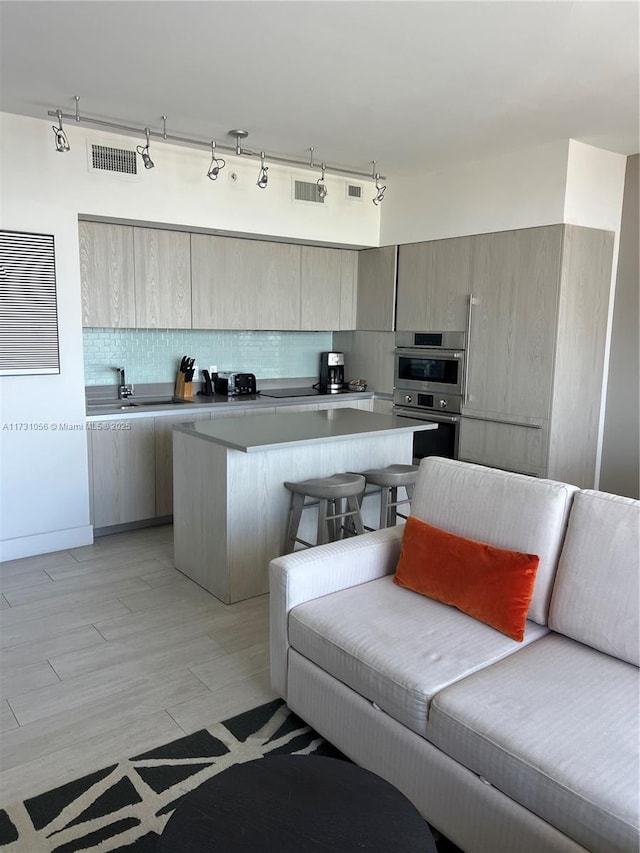 kitchen featuring a kitchen breakfast bar, a kitchen island, stainless steel double oven, light hardwood / wood-style floors, and backsplash