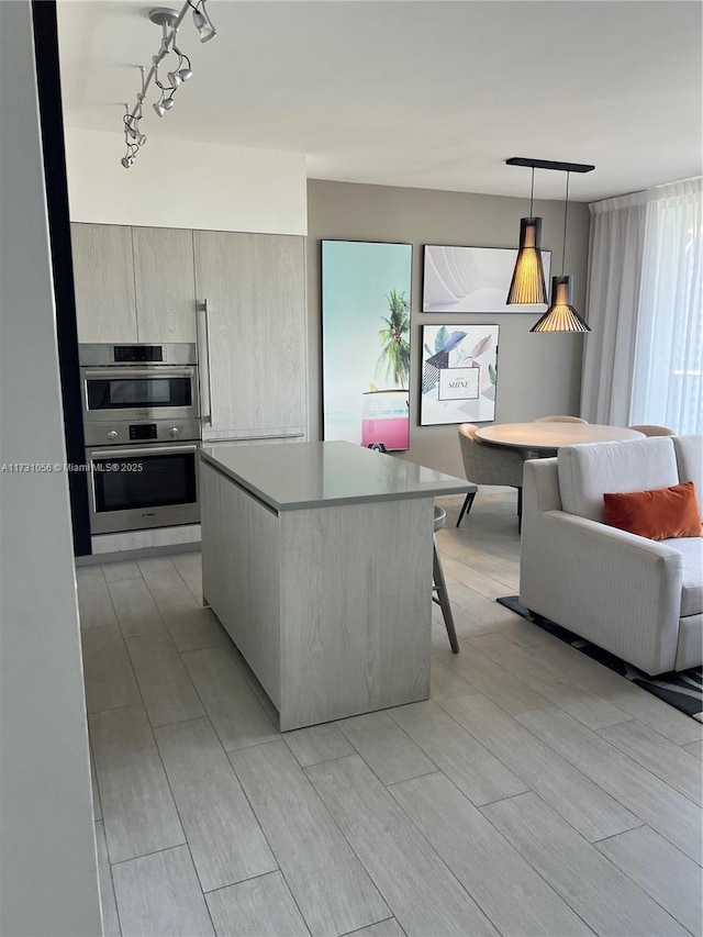 kitchen featuring a kitchen bar, a kitchen island, double oven, and hanging light fixtures