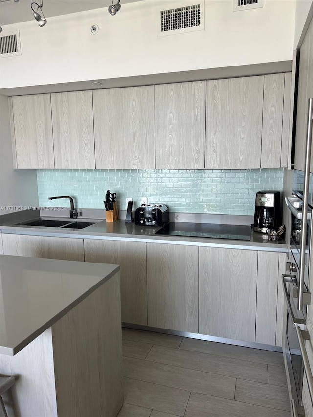 kitchen featuring tasteful backsplash, sink, light brown cabinetry, and black electric cooktop