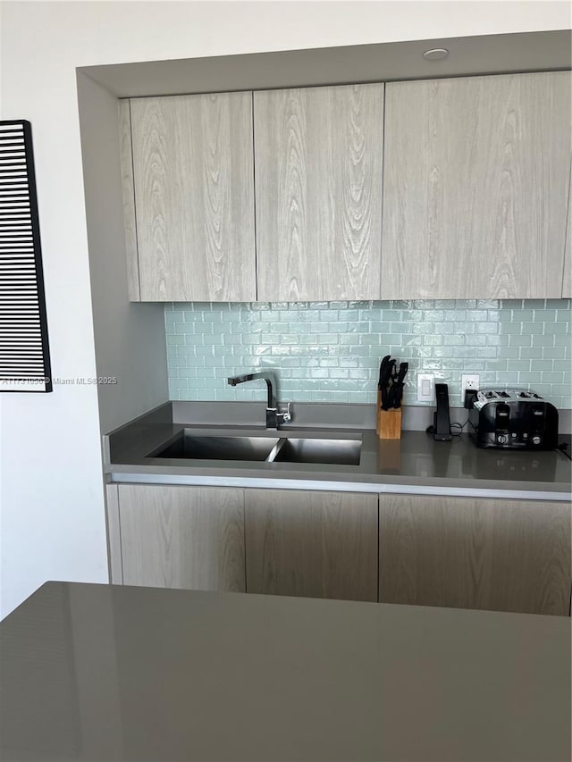 kitchen with tasteful backsplash, sink, and light brown cabinetry