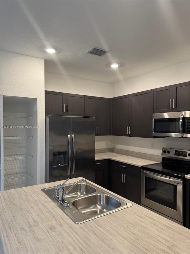 kitchen featuring appliances with stainless steel finishes, sink, and dark brown cabinets