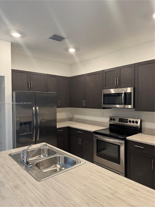 kitchen featuring appliances with stainless steel finishes, sink, and dark brown cabinets