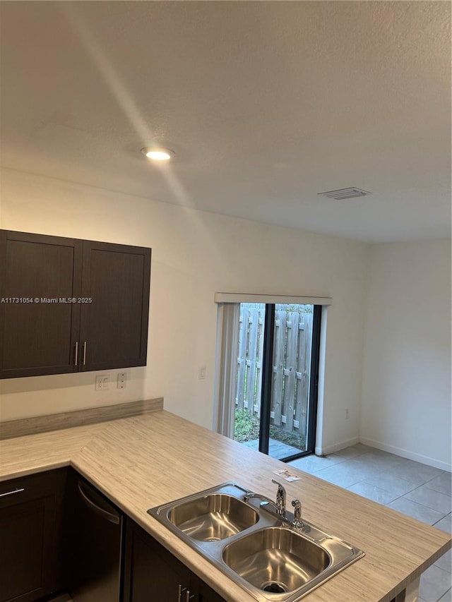 kitchen featuring kitchen peninsula, sink, dark brown cabinets, and light tile patterned floors