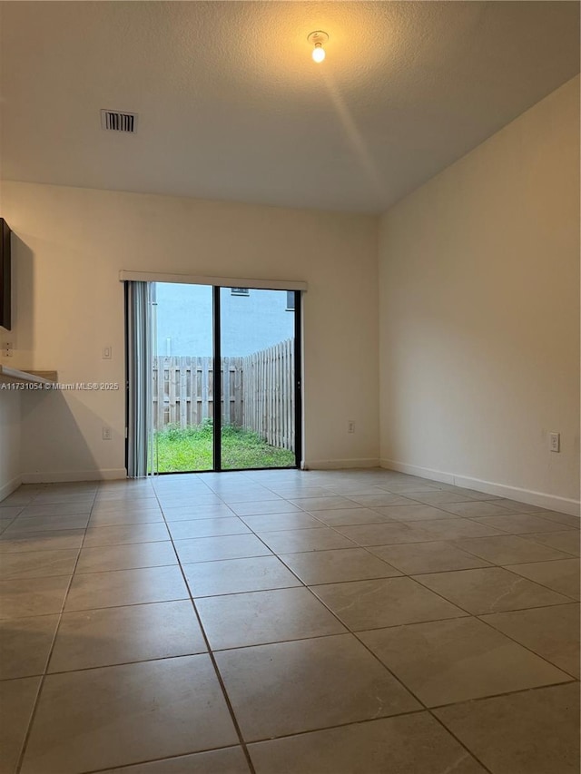 spare room with light tile patterned floors and a textured ceiling