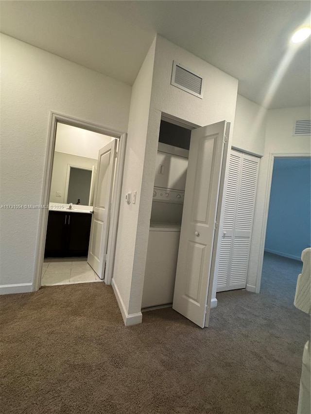 corridor featuring stacked washer and clothes dryer and carpet flooring