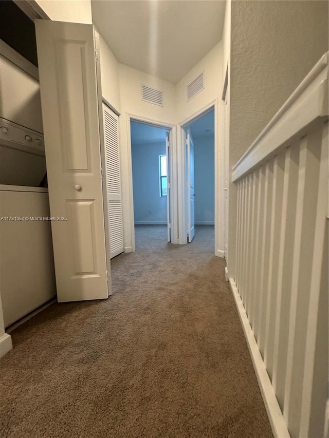 corridor featuring stacked washer / drying machine and carpet flooring