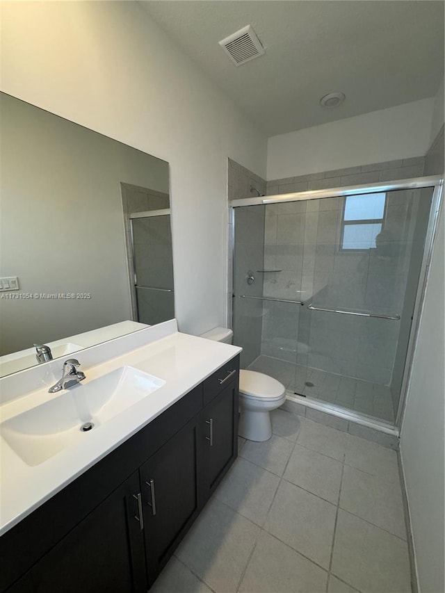 bathroom with vanity, toilet, tile patterned flooring, and a shower with door