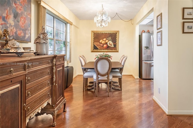 dining area with wood-type flooring and a chandelier