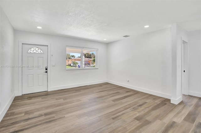 foyer featuring light wood-type flooring and a textured ceiling