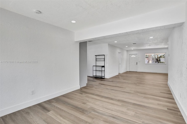 spare room featuring light wood-type flooring and a textured ceiling