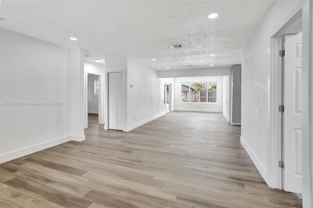 hallway with light hardwood / wood-style flooring and a textured ceiling