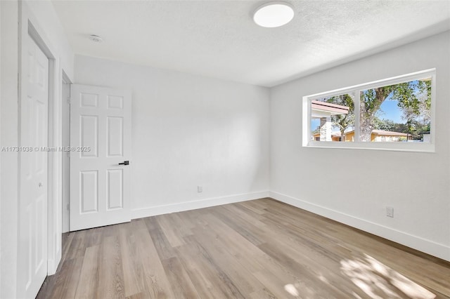 empty room with a textured ceiling and light wood-type flooring