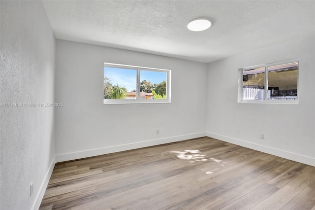 spare room with light hardwood / wood-style floors and a textured ceiling