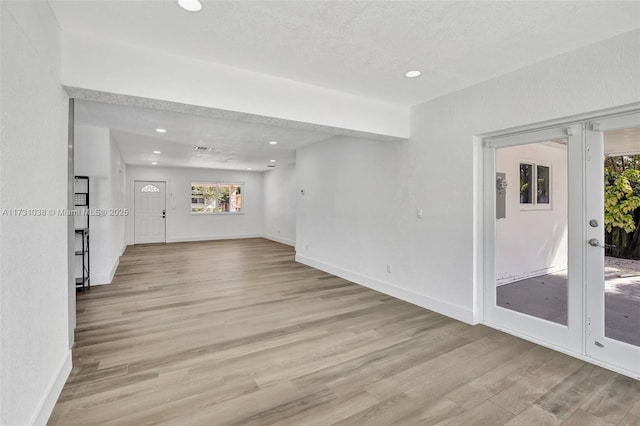 spare room featuring light wood-type flooring, a textured ceiling, and french doors