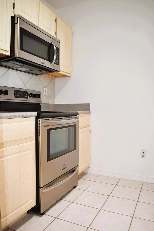 kitchen featuring baseboards, stainless steel appliances, light brown cabinets, backsplash, and light tile patterned floors
