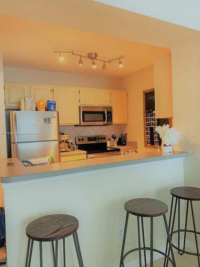 kitchen featuring light countertops, a breakfast bar area, backsplash, and appliances with stainless steel finishes