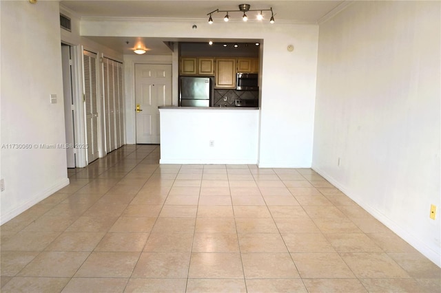 unfurnished room featuring baseboards, ornamental molding, and light tile patterned floors